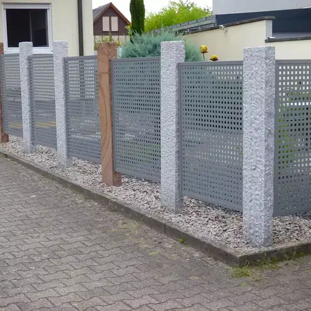 Moderner Gartenzaun aus Metall und Granitpfosten als Sichtschutz vor Wohnhaus.